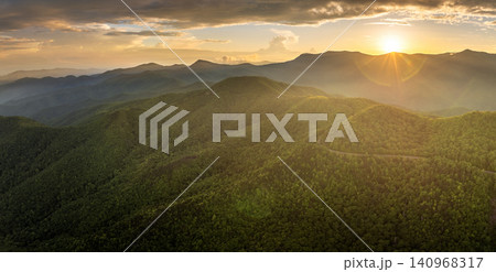 Winding mountain road in summer woods at sunset. Appalachian mountains in North Carolina with fresh green forest trees in summertime season. Beauty of USA nature Winding mountain road in summer woods at sunset. Appalachian mountains in North Carolina with fresh green forest trees in summertime season. Beauty of USA nature 140968317