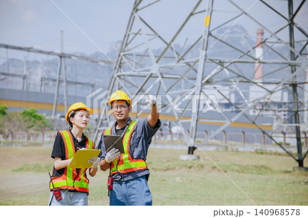 Electricity engineer working team against power plant background and power line survey inspector Electricity engineer working team against power plant background and power line survey inspector 140968578