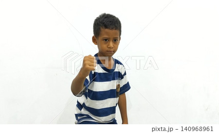 Determined Young Boy Raising His Fist with Serious Gaze Determined Young Boy Raising His Fist with Serious Gaze 140968961