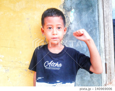 Determined Young Boy Raising His Fist with Serious Gaze Determined Young Boy Raising His Fist with Serious Gaze 140969006
