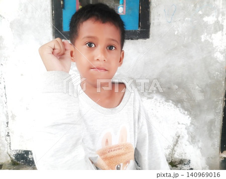 Determined Young Boy Raising His Fist with Serious Gaze Determined Young Boy Raising His Fist with Serious Gaze 140969016