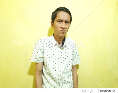 Young Asian Man Feeling Stressed with Headache Against Yellow Wall Young Asian Man Feeling Stressed with Headache Against Yellow Wall 140969612