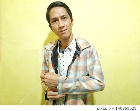 Young Asian Man Feeling Stressed with Headache Against Yellow Wall Young Asian Man Feeling Stressed with Headache Against Yellow Wall 140969629