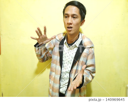 Young Asian Man Feeling Stressed with Headache Against Yellow Wall 140969645