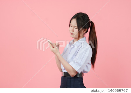 Thai student in uniform, Asian teen girl looking Smartphone seriously stress reading thinking Thai student in uniform, Asian teen girl looking Smartphone seriously stress reading thinking 140969767