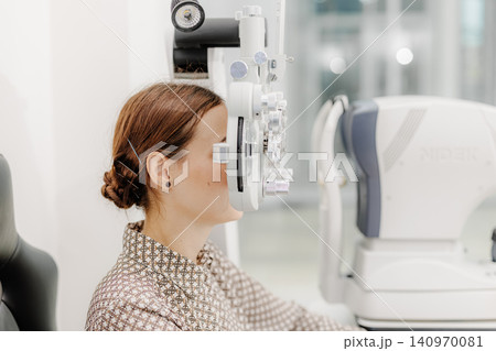 Optometrist performing eye examination with phoropter, vision test at ophthalmology clinic 140970081