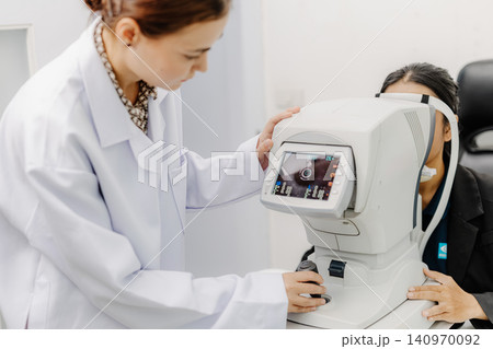 Optometrist performing eye examination with phoropter, vision test at ophthalmology clinic Optometrist performing eye examination with phoropter, vision test at ophthalmology clinic 140970092
