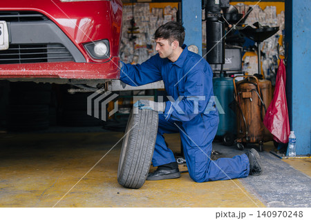Auto mechanic worker changing car tire in auto workshop garage, Vehicle tyre maintenance service 140970248