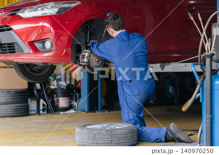 Auto mechanic worker changing car tire in auto workshop garage, Vehicle tyre maintenance service 140970250
