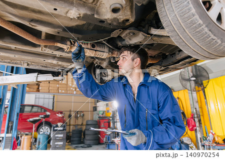 Garage Mechanic worker in auto service center working steering brake service maintenance under car. Garage Mechanic worker in auto service center working steering brake service maintenance under car. 140970254