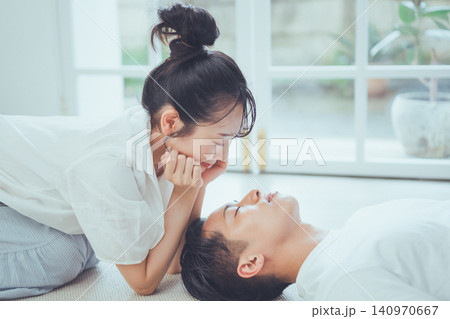 昼寝する彼氏の寝顔に顔を近づけ穏やかに微笑む彼女の甘くロマンティックなシーン 昼寝する彼氏の寝顔に顔を近づけ穏やかに微笑む彼女の甘くロマンティックなシーン 140970667