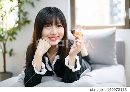 ベッドでドーナツを食べながらくつろぐ日本人女性 ベッドでドーナツを食べながらくつろぐ日本人女性 140972158