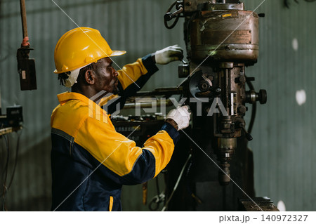 Professional African black Engineer male worker work with metal lathe machine in metal part factory 140972327