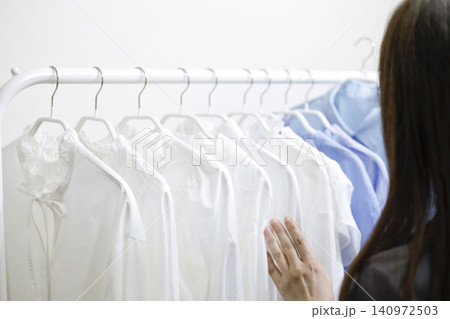 ハンガーラックに並んだ洋服を手に取る女性の後ろ姿 140972503