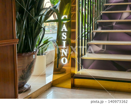Illuminated casino sign next to staircase and tropical plants in lobby Illuminated casino sign next to staircase and tropical plants in lobby 140973162