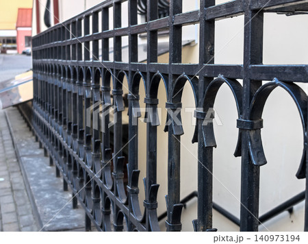 Black wrought iron fence with decorative arches in urban setting Black wrought iron fence with decorative arches in urban setting 140973194