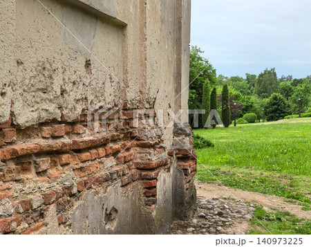 Old historic brick wall ruin with damaged plaster in green park landscape Old historic brick wall ruin with damaged plaster in green park landscape 140973225