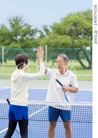 テニスでハイタッチをする笑顔のシニア夫婦・ダブルスの勝利 テニスでハイタッチをする笑顔のシニア夫婦・ダブルスの勝利 140974336