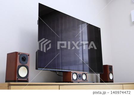 木製テレビボードに設置された大型テレビとホームシアターシステム 140974472