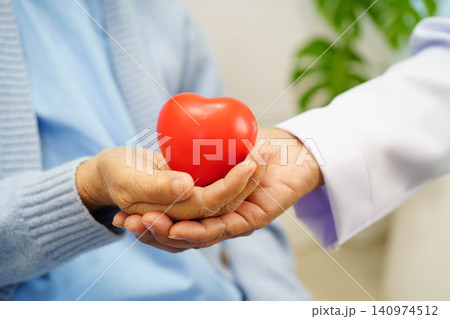 Asian elder senior woman patient holding red heart in hospital. Asian elder senior woman patient holding red heart in hospital. 140974512