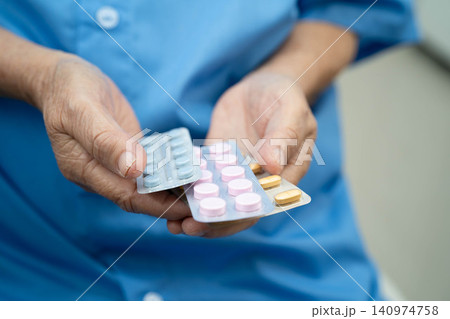 Asian elderly woman holding pill drug in hand, strong healthy medical concept. Asian elderly woman holding pill drug in hand, strong healthy medical concept. 140974758