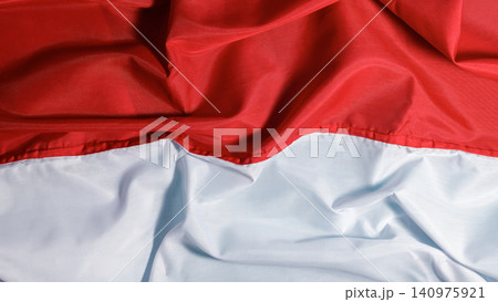 A close-up background texture of a rippled red and white cloth representing the national flag of Indonesia. High Quality Photo 140975921
