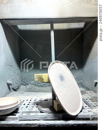 In a workshop, clay is shaped into ceramics as tools and materials surround the workspace, ready for production In a workshop, clay is shaped into ceramics as tools and materials surround the workspace, ready for production 140978057