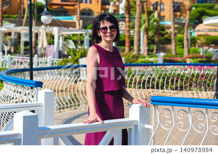 Portrait of a beautiful mature woman smiling on a sunny Egyptian resort with palm trees and blue sky Portrait of a beautiful mature woman smiling on a sunny Egyptian resort with palm trees and blue sky 140978984