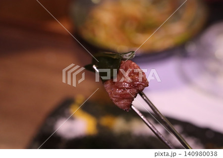 Grilled Meat with Leaf on Tongs Close-up Grilled Meat with Leaf on Tongs Close-up 140980038