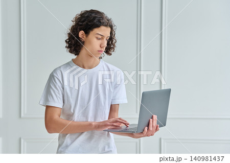 Teen boy with laptop studying online in studio 140981437