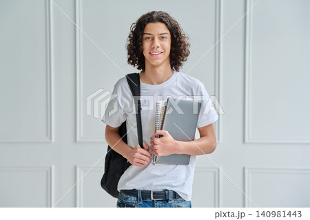 Teen student guy with laptop and backpack indoors Teen student guy with laptop and backpack indoors 140981443