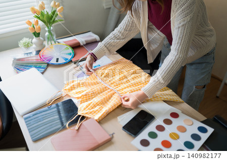 Fashion designer selecting fabric swatches with color wheel and samples on workspace table Fashion designer selecting fabric swatches with color wheel and samples on workspace table 140982177