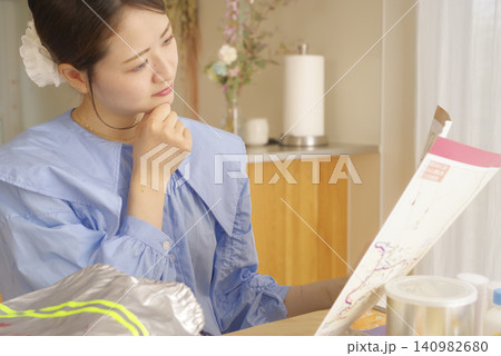 ハザードマップと防災用品を確認する女性 140982680
