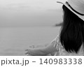 Rear view of a peaceful woman sitting by the sea in monochrome. Solitude, mindfulness, emotional healing, mental wellness, quiet reflection, minimal lifestyle, calm nature. Inner peace, resilience. 140983338