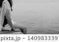 A woman sitting on a wooden pier beside calm water. Solitude, mindfulness, emotional healing, mental wellness, quiet reflection. Inner peace, resilience, meditation, emotional recovery, wellness. 140983339