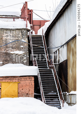snow-covered stairs in courtyard of idle factory 140984275