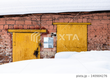 snowdrift and yellow painted doors in brick hangar snowdrift and yellow painted doors in brick hangar 140984276