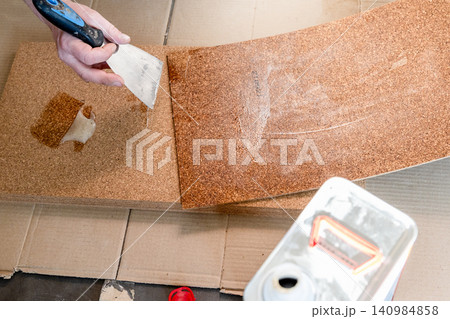 floor layer applies adhesive to cork tile floor layer applies adhesive to cork tile 140984858
