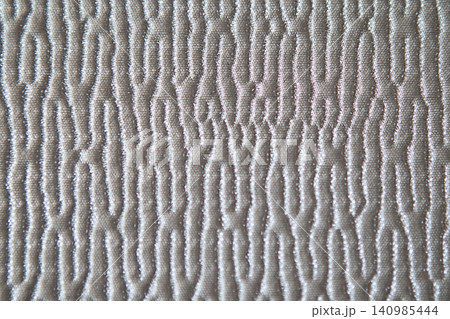 Quilted beige fabric texture with embossed wavy pattern close-up for background and design Quilted beige fabric texture with embossed wavy pattern close-up for background and design 140985444