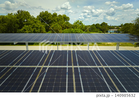 Aerial view of solar panels installed as shade roof over parking lot for parked cars for effective generation of clean electricity. Photovoltaic technology integrated in urban infrastructure Aerial view of solar panels installed as shade roof over parking lot for parked cars for effective generation of clean electricity. Photovoltaic technology integrated in urban infrastructure 140985632