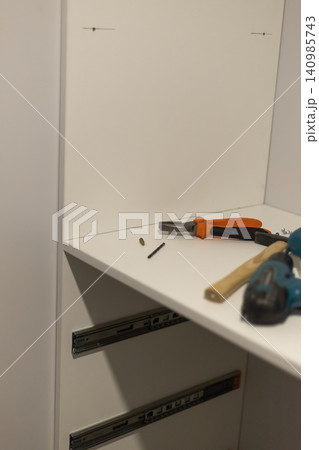 Power tools and hardware on white shelf in home office Power tools and hardware on white shelf in home office 140985743