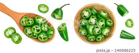 sliced jalapeno pepper in wooden bowl and spoon isolated on white background. Green chili pepper . Top view. Flat lay sliced jalapeno pepper in wooden bowl and spoon isolated on white background. Green chili pepper . Top view. Flat lay 140986225