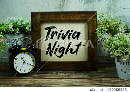 Trivia Night text with alarm clock on wooden background Trivia Night text with alarm clock on wooden background 140986336