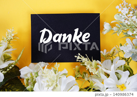 Danke text written on paper card with flowers decoration on yellow background Danke text written on paper card with flowers decoration on yellow background 140986374