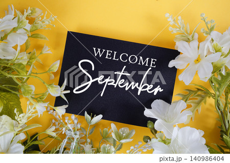 Welcome September text written on paper card with flowers decoration on yellow background 140986404