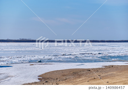 Urban landscape of Khabarovsk riverbank featuring melting ice and clear sky Urban landscape of Khabarovsk riverbank featuring melting ice and clear sky 140986457