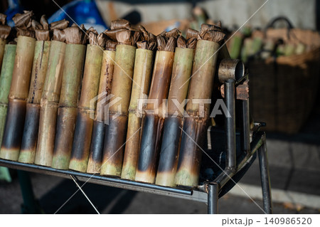 Preparation of dessert Khao Lam or Lemang, sticky rice slow-roasted inside bamboo shoots over coals Preparation of dessert Khao Lam or Lemang, sticky rice slow-roasted inside bamboo shoots over coals 140986520