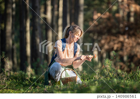 Positive woman hobbyist forager checking fresh Boletus edulis mushroom stem with knife for worms. 140986561