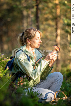 Smiling woman mushroomer forager found fresh edible boletus mushrooms in autumn pine forest. 140986597