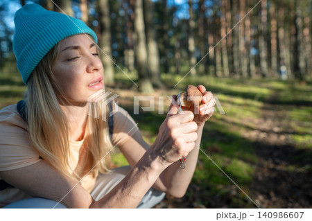 Woman hobbyist forager checking fresh Boletus edulis mushroom stem with knife for worms. 140986607